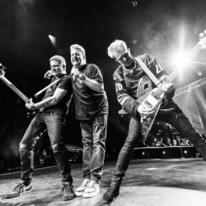 Jay DeMarcus, Gary LeVox, and Joe Don Rooney performing on stage.